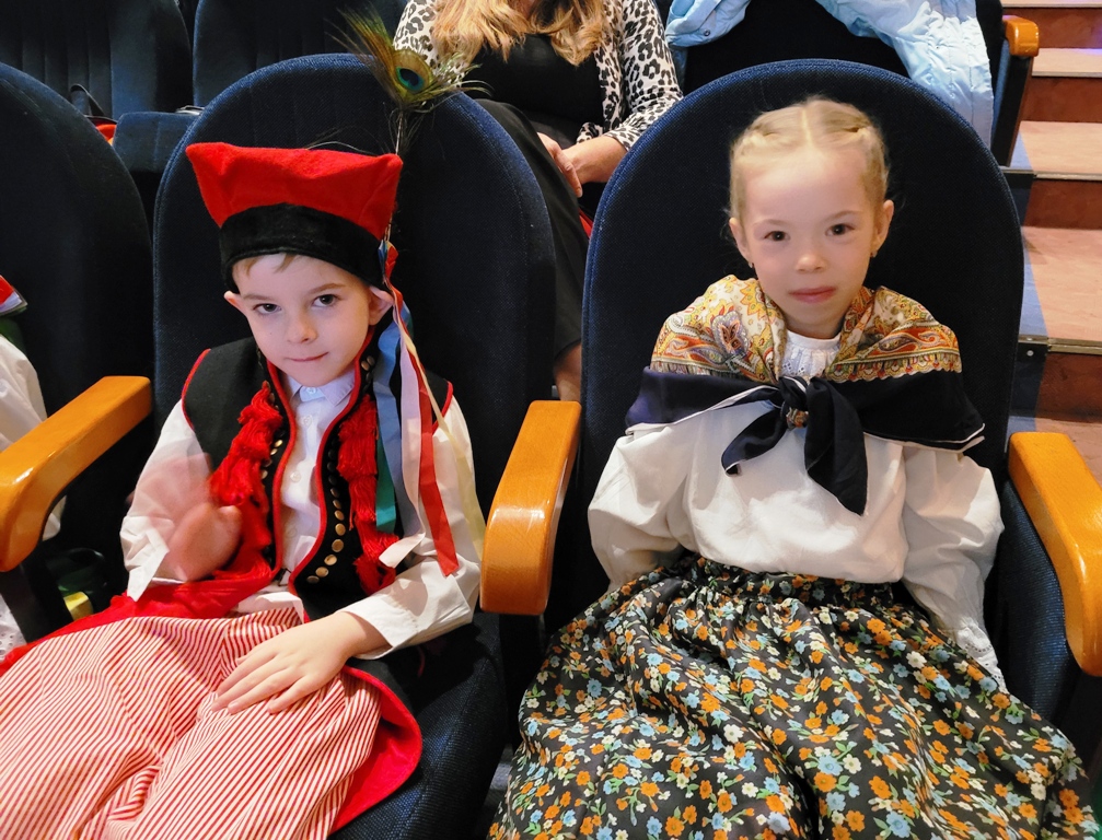 Zdjęcie przedstawia dwoje dzieci z grupy ”Biedronek” siedzące na widowni w oczekiwaniu na występ.