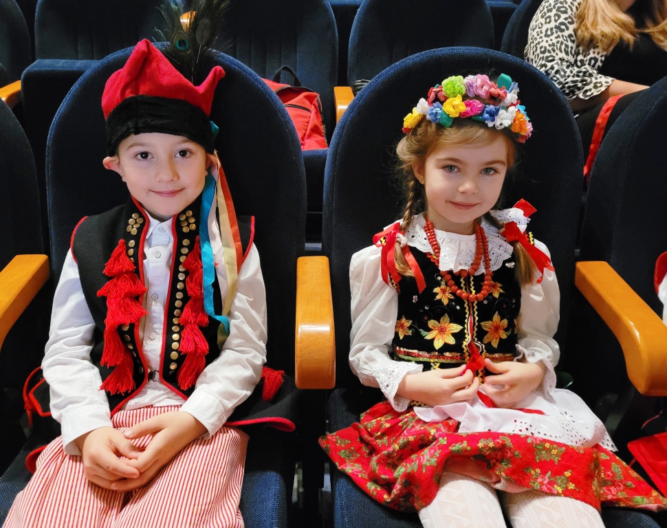 Zdjęcie przedstawia dwoje dzieci w strojach krakowskich z grupy ”Biedronek” siedzące na widowni w oczekiwaniu na występ.