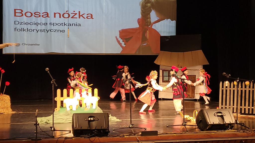 Zdjęcie przedstawia dzieci z grupy „ Biedronek” tańczące „Krakowiaka” na scenie MOKSIR.