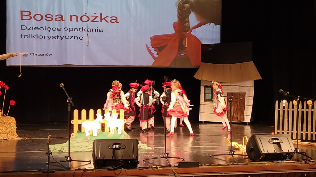 Zdjęcie przedstawia dzieci z grupy „ Biedronek” tańczące „Krakowiaka” na scenie MOKSIR.