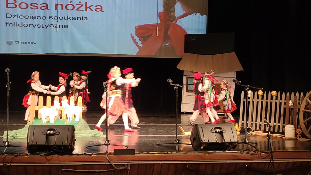 Zdjęcie przedstawia dzieci z grupy „Biedronek” tańczące „Krakowiaka” na scenie MOKSIR.