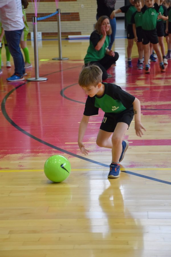 Chłopiec podczas konkurencji sportowej toczy piłkę.