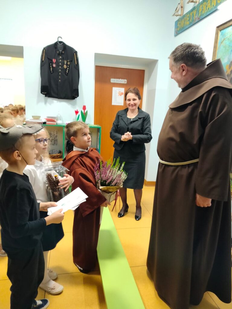 Dzieci z grupy Biedronek wręczają ojcu Lesławowi prezent w podziękowaniu.