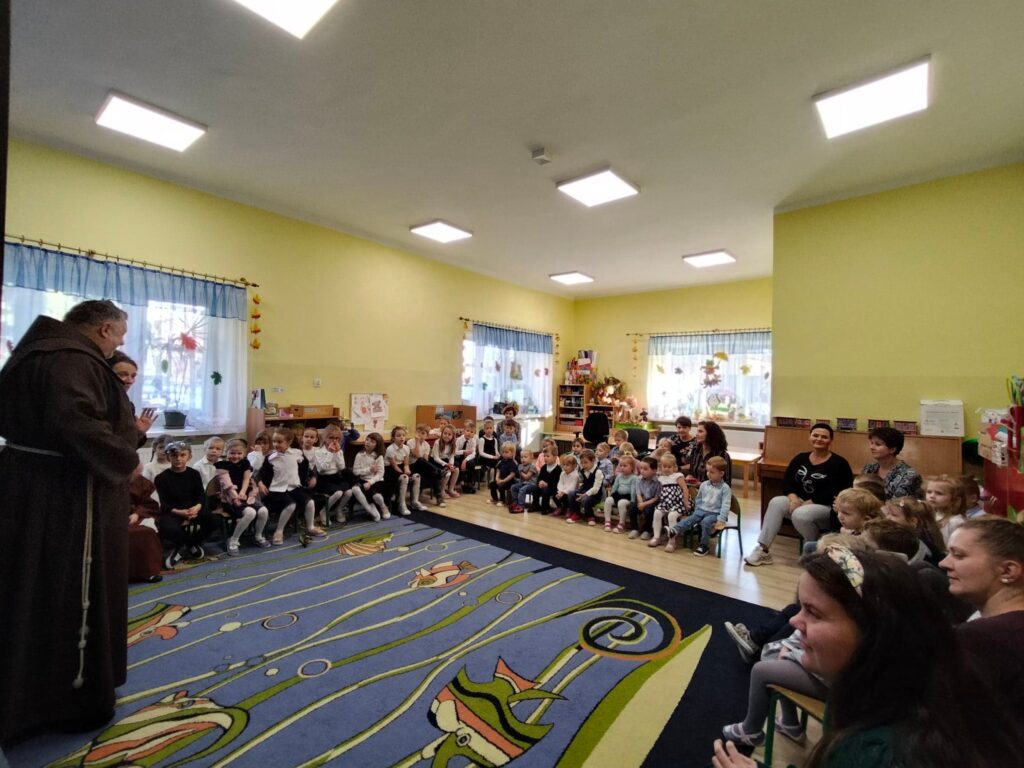 Przedszkolaki oraz pracownicy słuchają ojca Lesława.