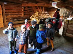 Dzieci z zainteresowaniem oglądają drewniany budynek.