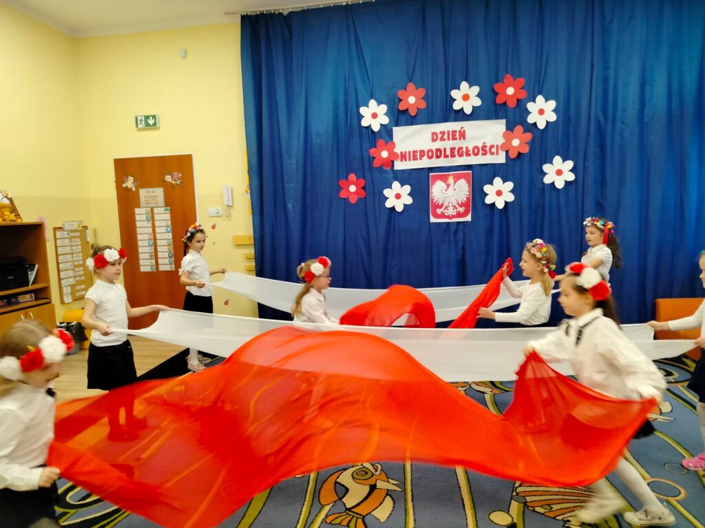 Dziewczynki tańczą z chustami w barwach flagi Polski.
