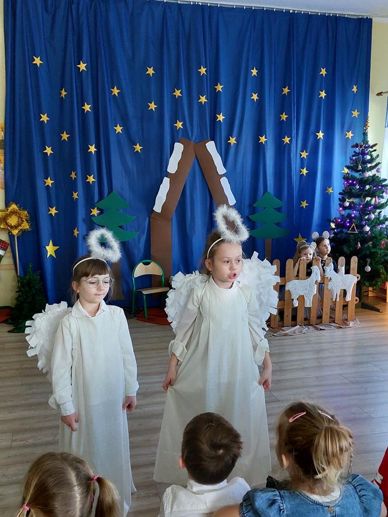 Dziewczynki w strojach aniołków występują na scenie.
