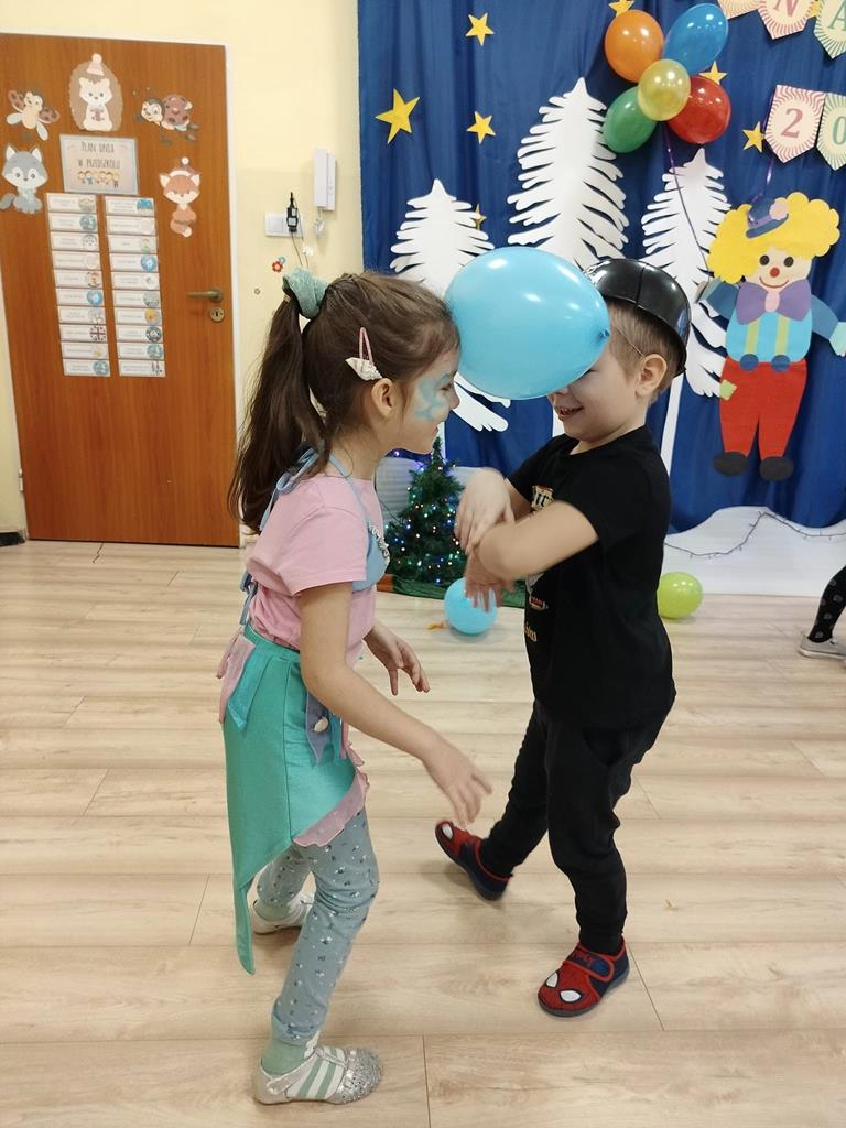 Chłopiec i dziewczynka tańczą z balonem.
