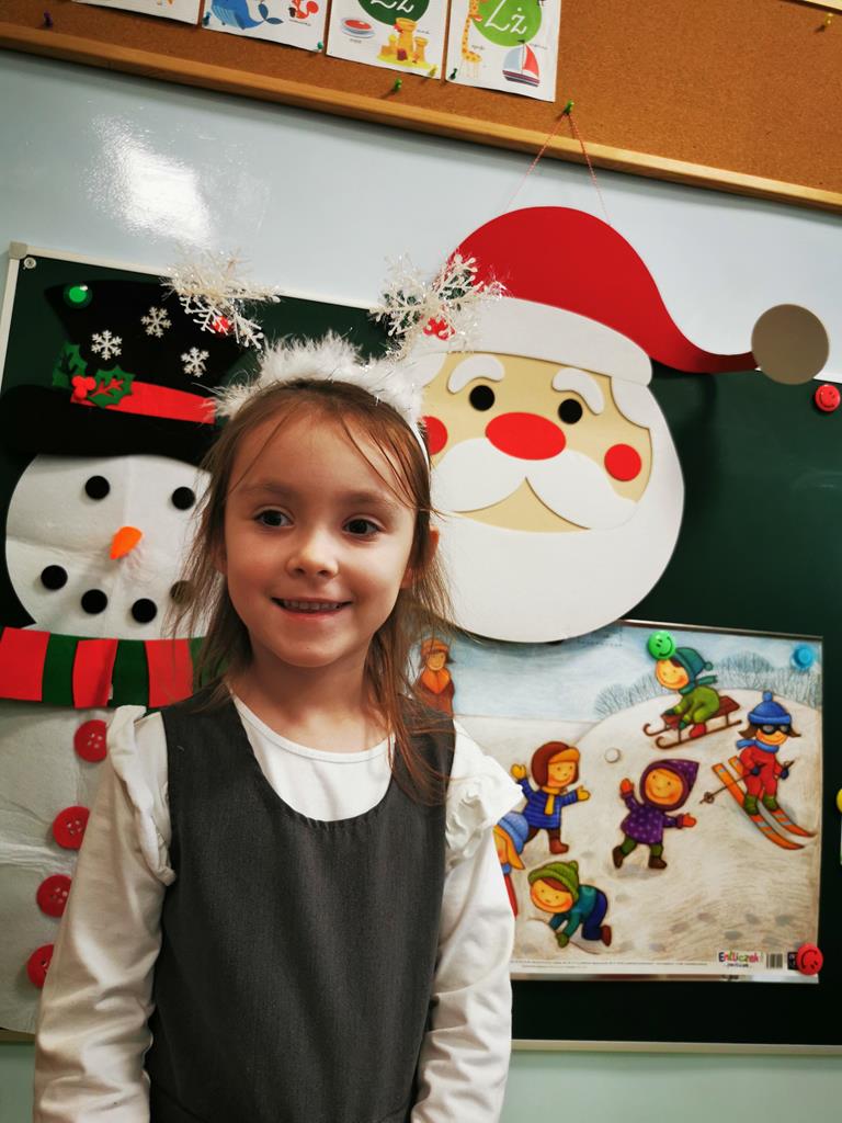 Dziewczynka pozuje do zdjęcia w opasce ze śnieżynkami.
